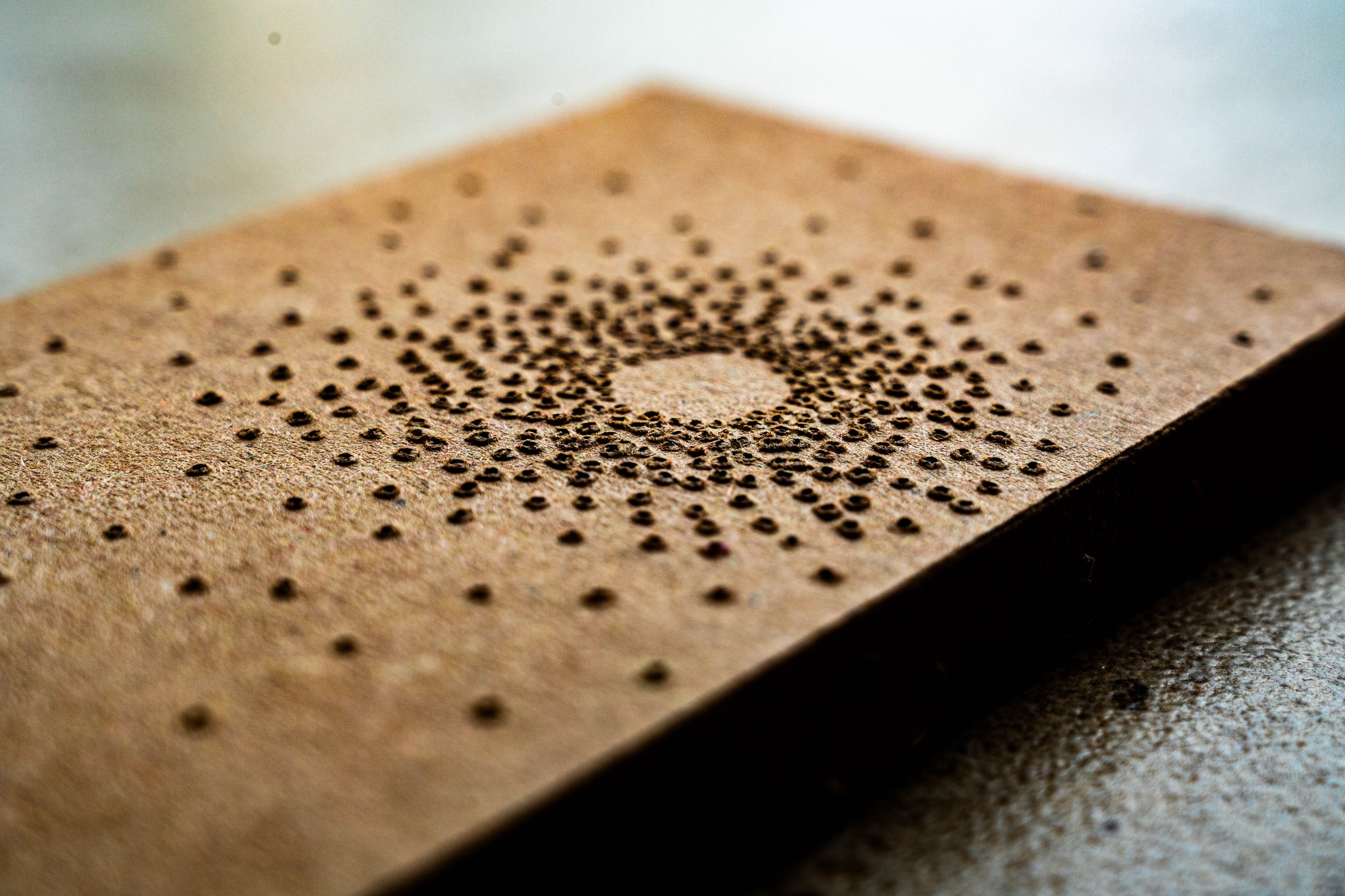 Point of Light packaging, macro detail of the perforated cardboard showing the physical depth and thickness of the holes